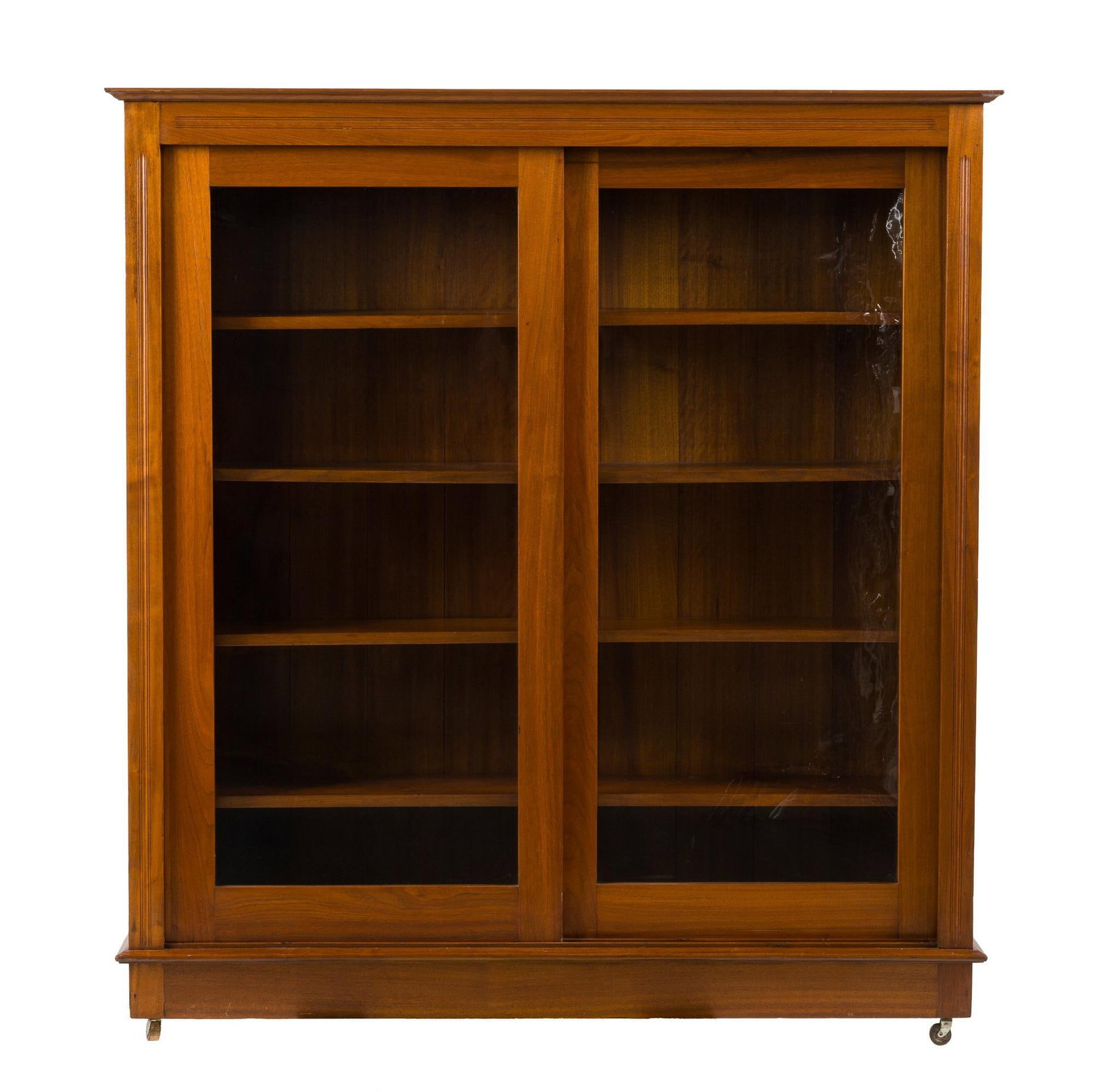 Edwardian Bookcase: An early 20th century mixed woods Edwardian bookcase with sliding double glazed doors Piece may have been a built in that wheels were later added to for convenience. Refinished, wear consistent
