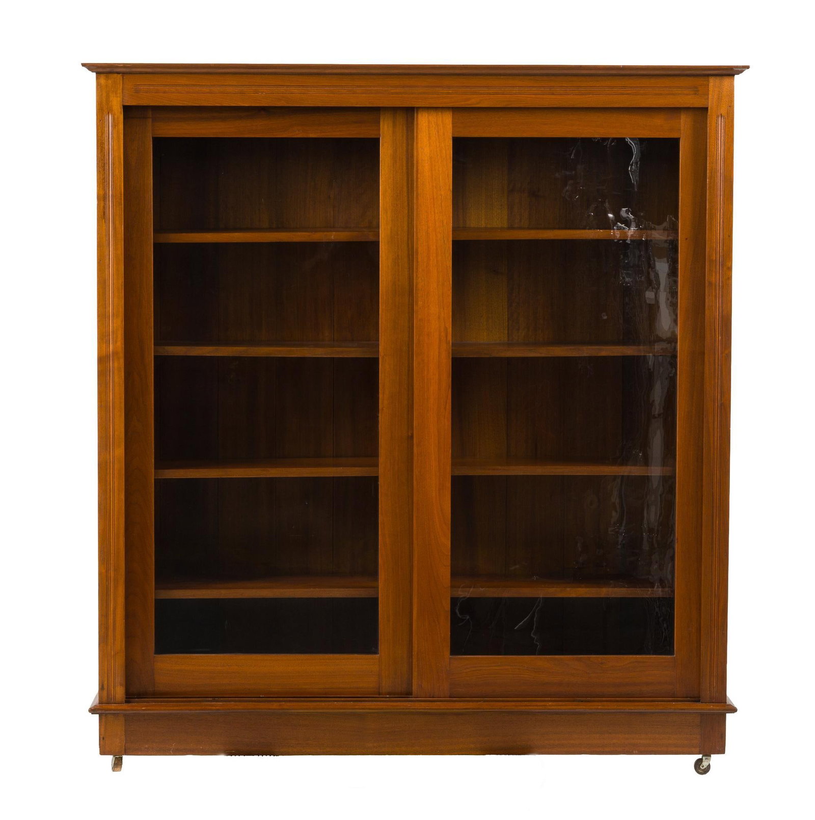 Edwardian Bookcase: An early 20th century mixed woods Edwardian bookcase with sliding double glazed doors Piece may have been a built in that wheels were later added to for convenience. Refinished, wear consistent with
