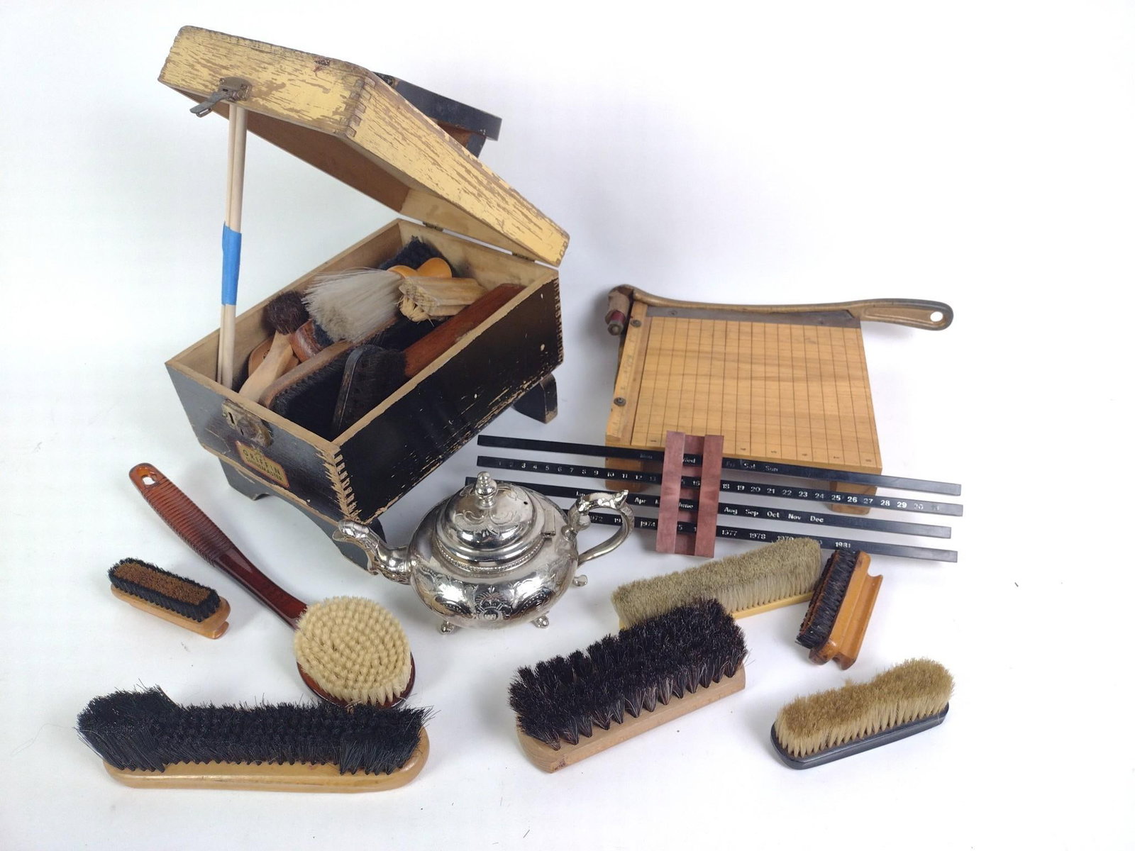 Silverplate, Shoe Shine, and More: Shoe shine box and brushes, silverplate teapot, paper cutter and desk accessories. 8" to 9-1/4" wide x 10-1/2" to 14" long. 