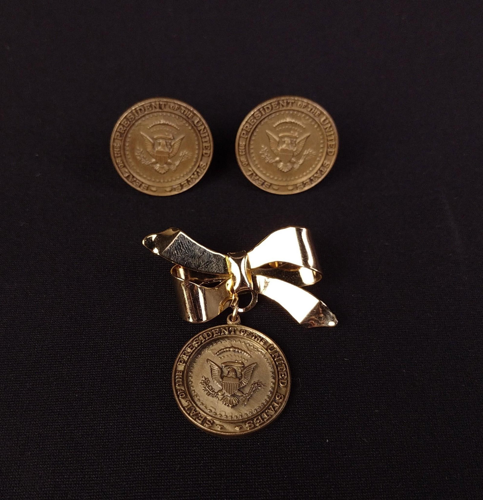 Nixon Presidential Seal Cufflinks & Bow Brooch: Includes pair of presidential cufflinks and bow pin. Cufflinks and medallion on pin measure 1" diameter. Provenance: From the Estate of Lory Patrick Jones (1933–2026), actress, writer
