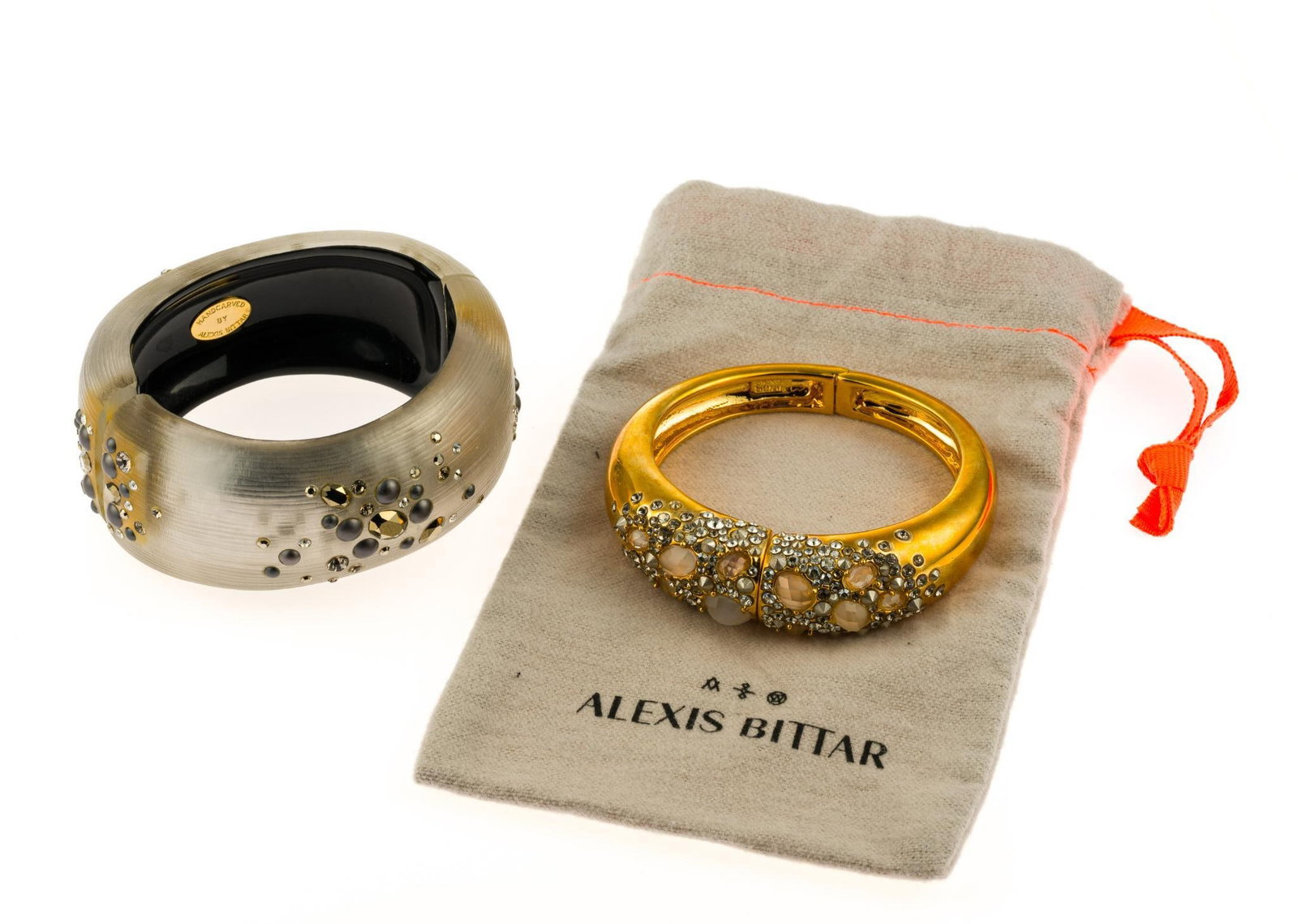 2 Alexis Bittar Bangle Bracelets: Both are hinged bangle designs with one being gold tone and the second hand carved lucite or resin, both with rhinestone decorations. One includes dust bag. 2-1/4" to 2-3/8" inside dimensions. 