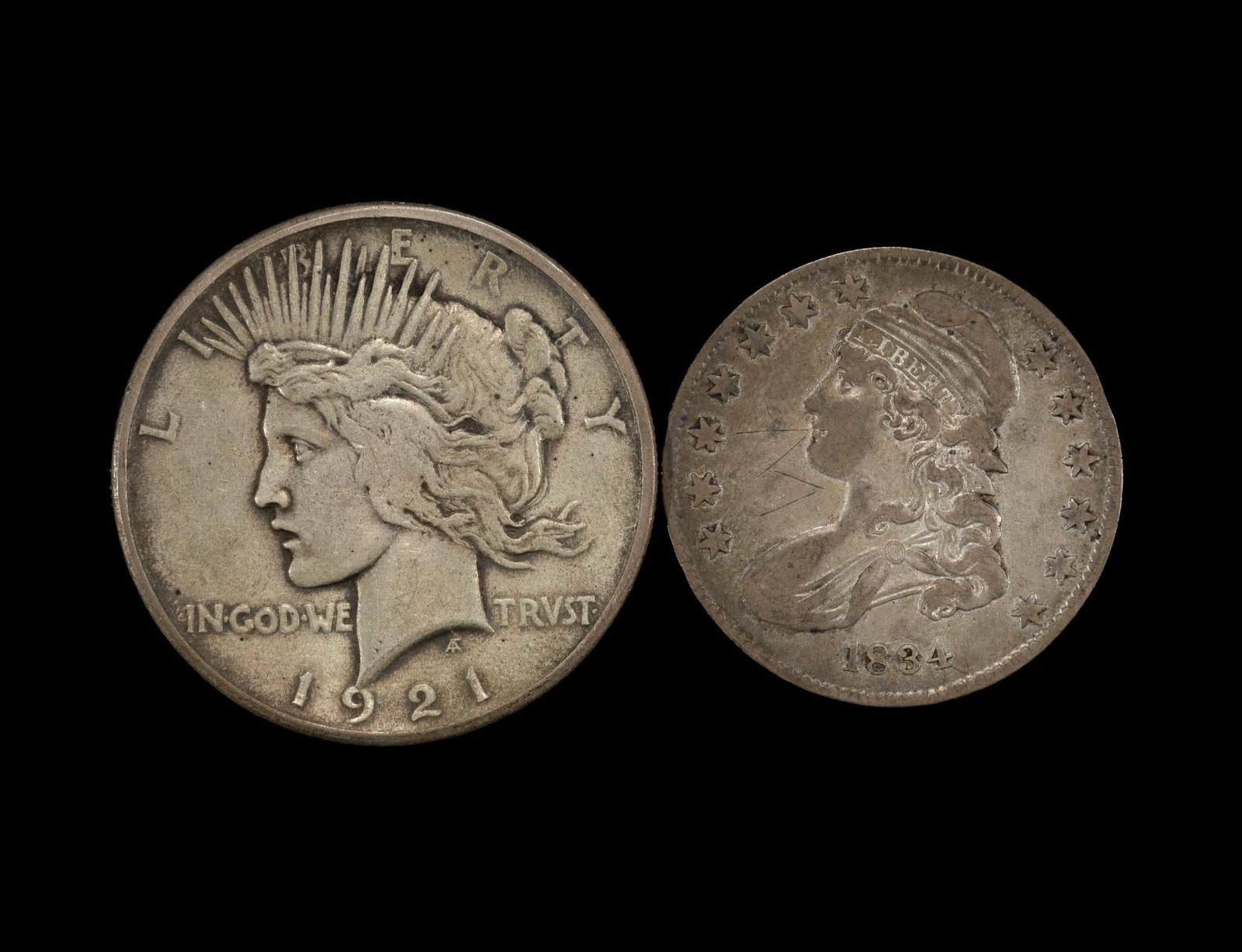 1921 Peace Dollar And Capped Bust Half: The Peace dollar is approximately XF40 with no damage or past cleaning evidence. The 1834 capped bust half is VF details with V scratches obverse left field.