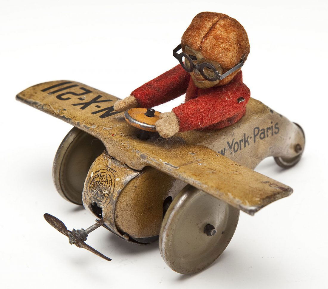 Schuco Spirit of St. Louis Tin Friction Airplane: DESCRIPTION: Schuco Spirit of St. Louis tin litho friction toy with felted figure of Charles Lindbergh. Marked "N-X-211" to right wing. Body with Schuco mark to front. Sides marked "New York-Paris". M