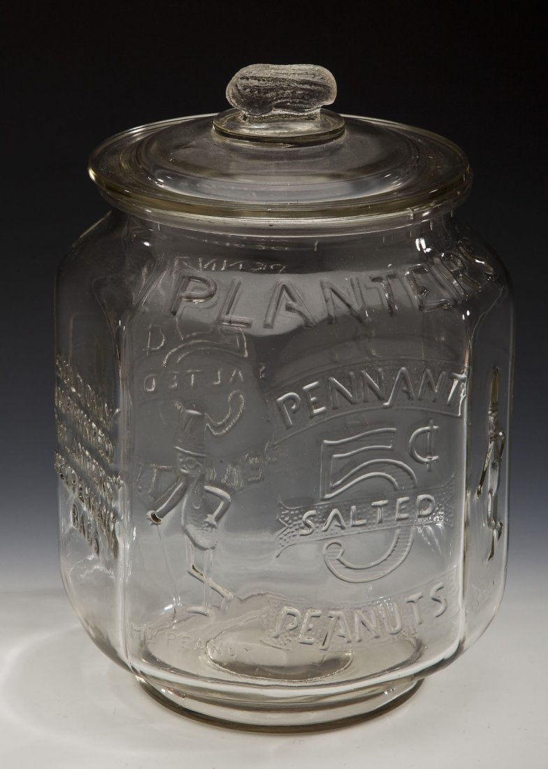 Early 20th C Large Glass Planters 5¢ Peanut Jar: DESCRIPTION: Early 20th century large glass Planters 5¢ Peanut jar with lid. Lid with figural peanut finial. Octagonal shaped jar with raised details. The four smaller sides showing Mr. Peanut with h