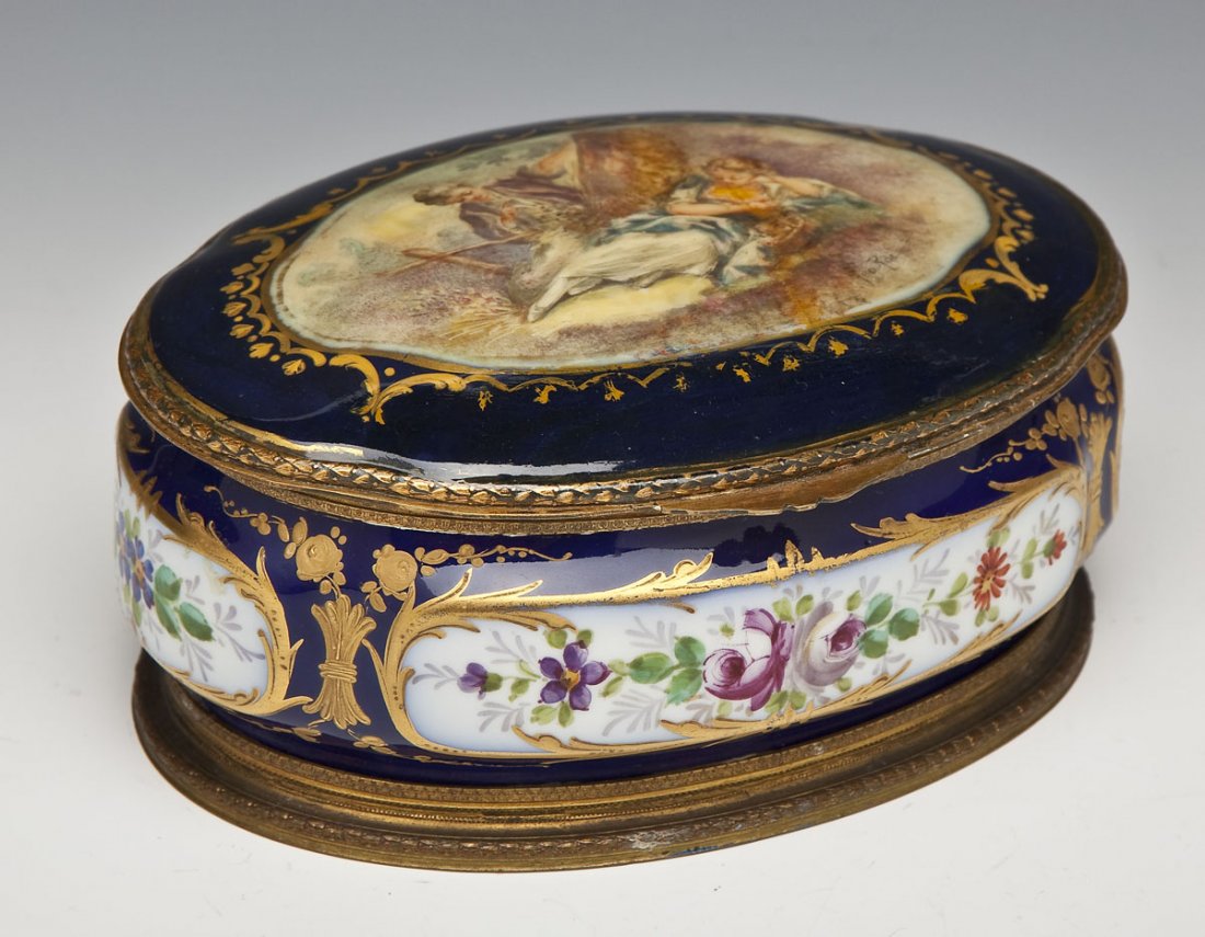 Sevres Trinket Box Signed Geo. Rochet: DESCRIPTION: Sevres porcelain trinket box with ormolu mounts. The lid with patined scene of two figures signed "Geo. Rochet". Base painted with sections of floral detailing all on a gilt trimmed cobal