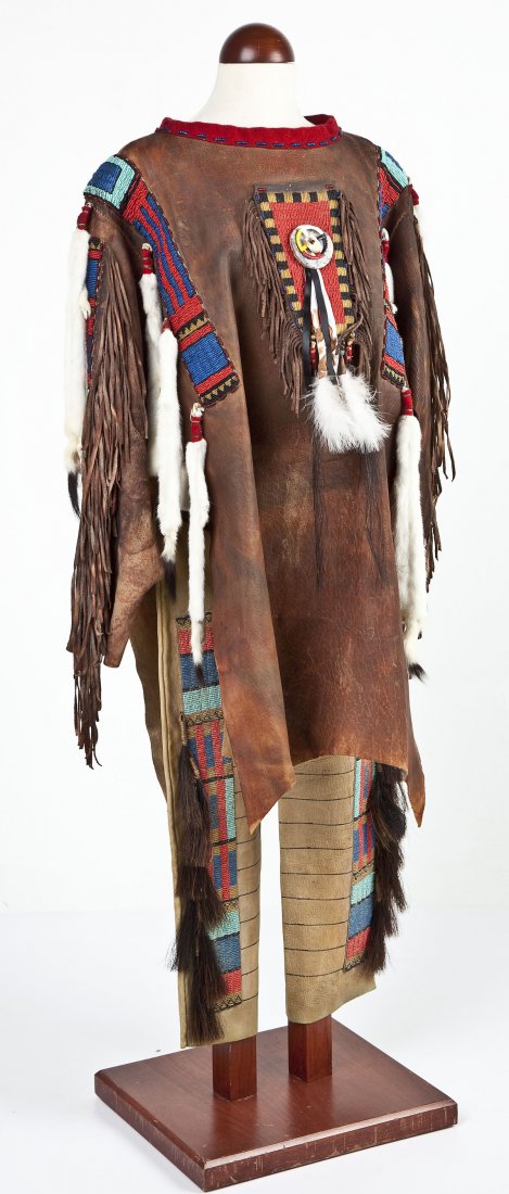 Signed Beaded War Shirt & Leggings: DESCRIPTION: Elk hide war jacket with red, blue, and black beaded panels with fur. Signed indistinctly. Together with a pair of leather beaded leggings by association. MEASUREMENTS: 20" x 35". CONDITI