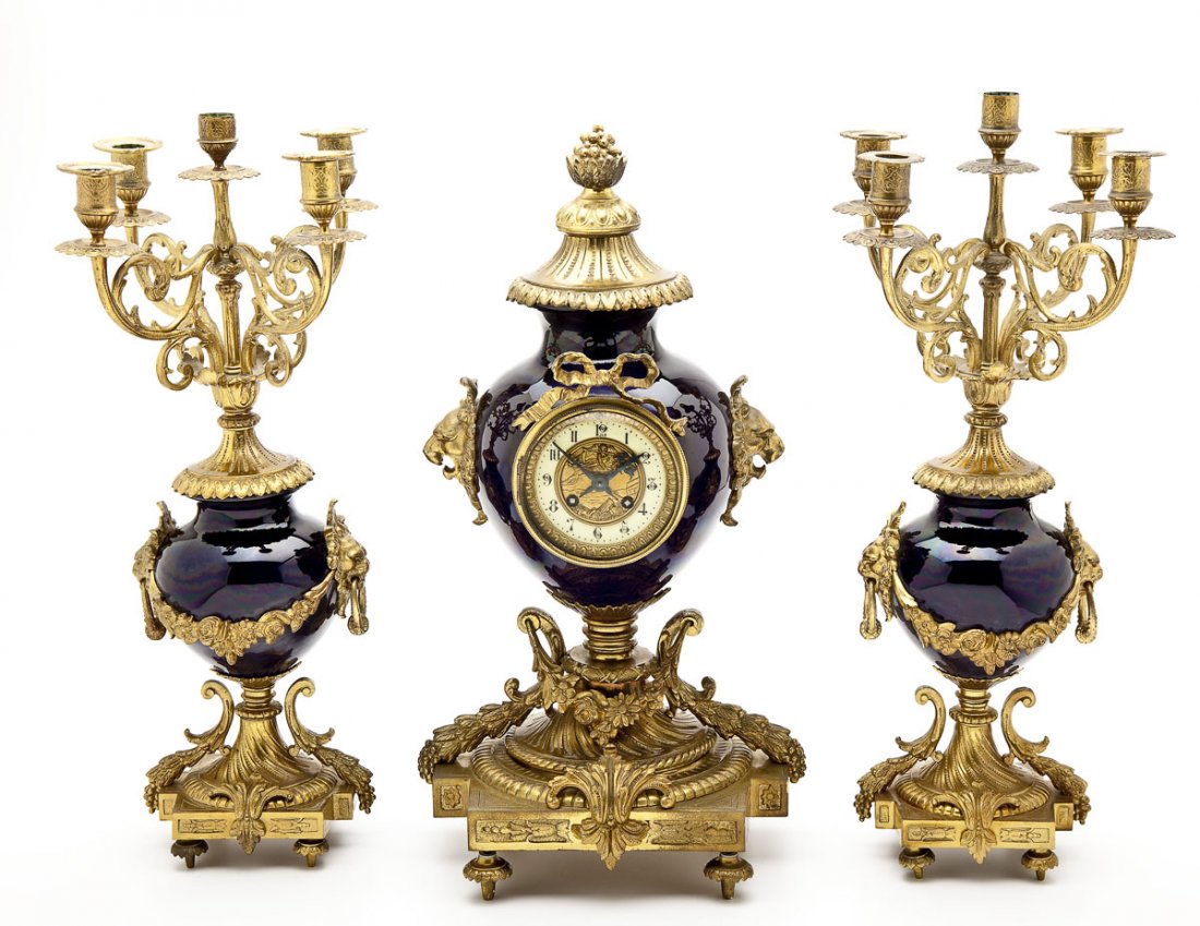 Sevres Ormolu & Porcelain Clock Garniture: DESCRIPTION: French clock garniture set attributed to Sevres. Comprising a clock and two matching candelabras in cobalt blue porcelain with ormolu mounts. Urn form clock with ribboned bezel flanked by