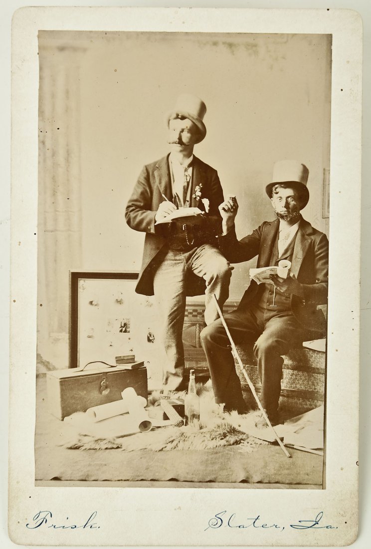 Vaudeville Act Cabinet Card: DESCRIPTION: Cabinet card of a possible vaudeville or comedy act. Portrays two gentlemen in top hats with papers, cane, empty bottle, corn cob, papers, suitcase and framed photo. Written to lower marg