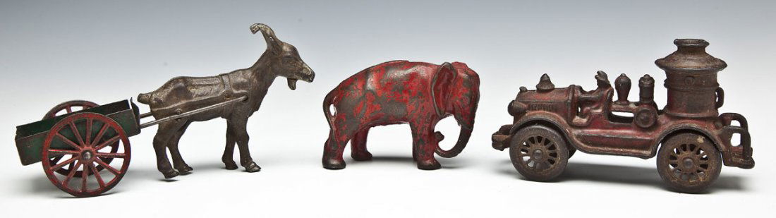 3 Antique Cast Iron Toys: DESCRIPTION: Three cast iron toys. Includes: 1) Red painted fire engine pumper car. 6-1/4" long x 3-1/2" high. 2) Red painted elephant still bank. 4" long x 3" high. 3) Kenton goat pulling a painted t