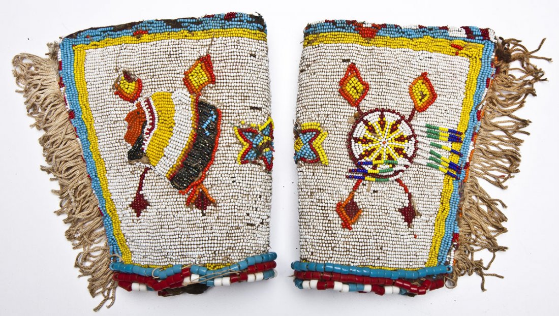 Pair Six Nations Beaded Gauntlets: DESCRIPTION: Pair of Six Nations beaded and fringed gauntlets or cuffs. Each with polychrome beading, one with profile of chief and the other of a drum or mandela. Retains older tag "Beaded Cuffs by M