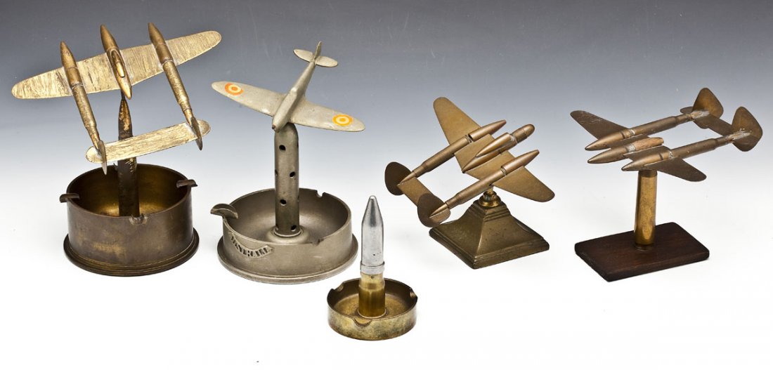 Collection of 5 Pieces of Trench Art: DESCRIPTION: Collection of 5 pieces of trench art. Including: depictions of 4 planes and one piece of ordinance converted to a lighter. 3 of the pieces are ashtrays. MEASUREMENTS: Range from 5" to 7-1