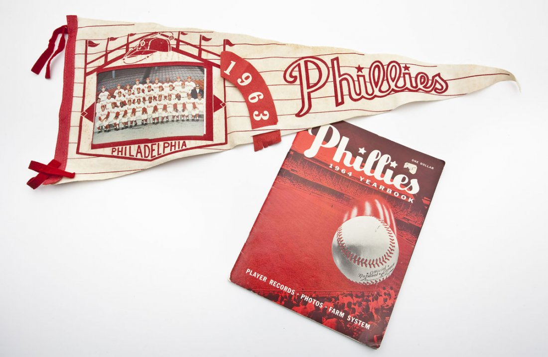 Philadelphia Phillies Pennant and Yearbook: DESCRIPTION: Lot of two Philadelphia Phillies memorabilia including a 1963 picture pennant and a 1964 team yearbook. MEASUREMENTS: Pennant 29-3/4" x 11-1/2" at widest point. Yearbook 8-1/2" x 11". CON