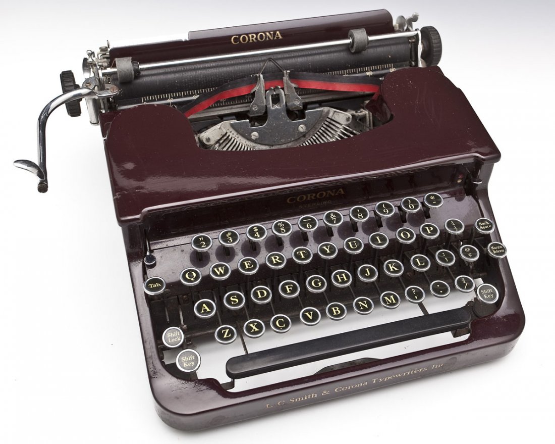 L.C. Smith and Corona Sterling Maroon Typewriter: DESCRIPTION: L.C. Smith and Corona Sterling maroon typewriter. Circa 1930s. In black fabric covered wooden case. All keys present. Black leather handle. MEASUREMENTS: Case 13-1/4" x 13-1/4" x 5-7/8" h