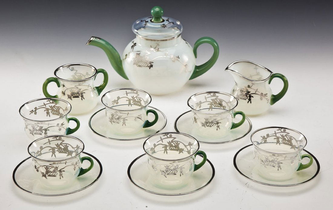 Rockwell Silver Overlay Glass Tea Set: DESCRIPTION: Rockwell silver overlay tea set on opalescent glass with green handles. Comprises a 6-1/2" tea pot, 3-1/2" sugar, 3" creamer, six 2-1/4" tea cups and five 5-1/2" saucers. With etched Rock