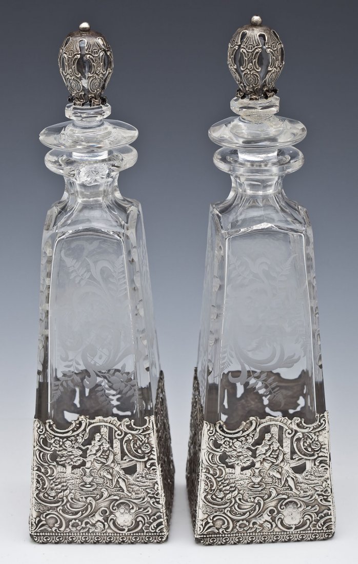 Pair of Mauser Sterling and Glass Decanters: DESCRIPTION: Pair of Mauser sterling overlay and glass decanters. Etched glass with floral and scroll motif. Each with sterling around stoppers and surrounding bases of decanters. Sterling around base