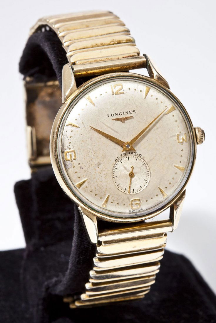 Man's Longines Automatic Wristwatch: DESCRIPTION: Man's Longines goldfilled wristwatch. Metallic dial with gold numeral markers and hands, subsidiary seconds, marked "Longines Automatic Swiss". On a Gemex stretch bracelet. MEASUREMENTS: