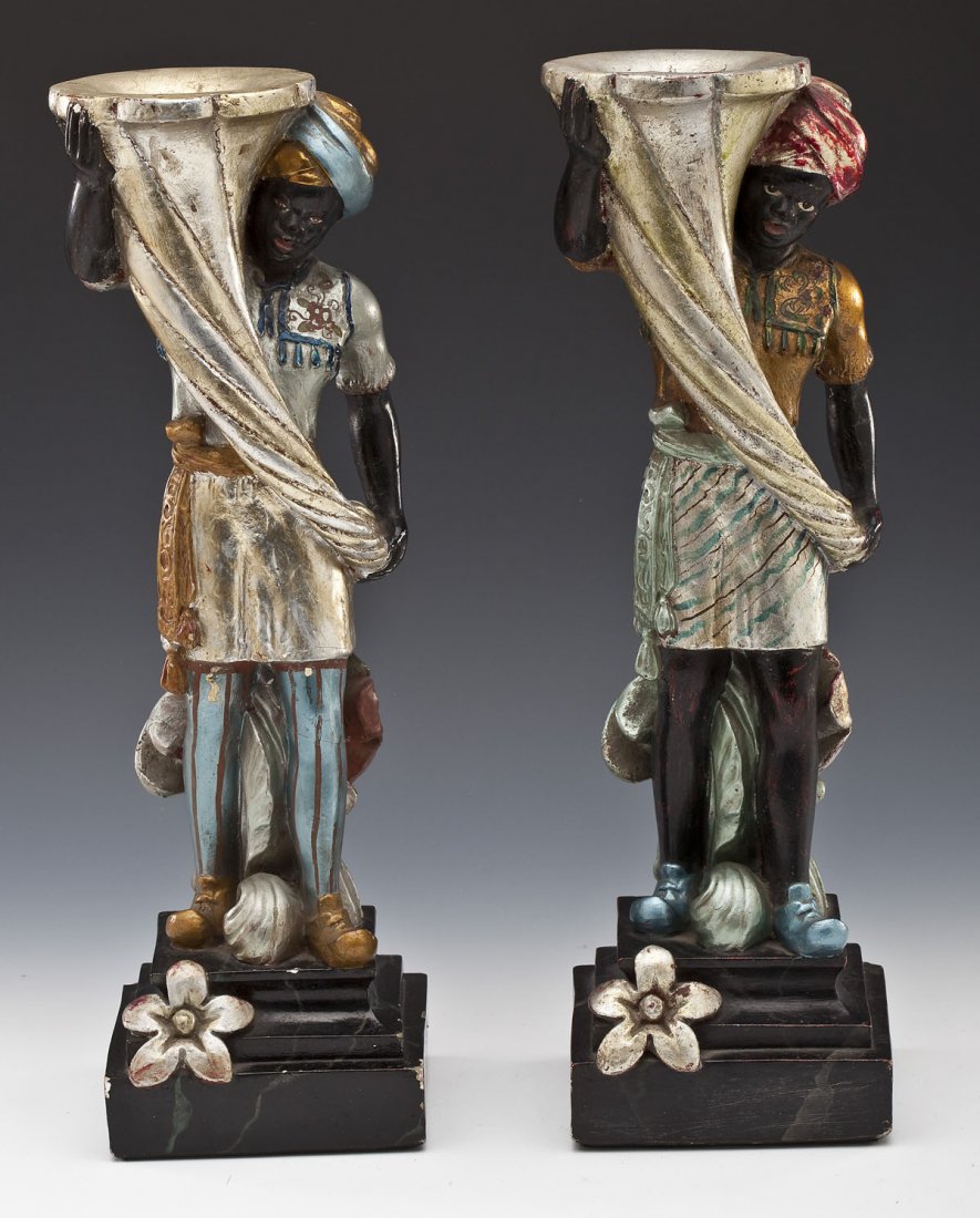 Pair of Gessoed Plaster Blackamoor Figures: DESCRIPTION: A pair of polychrome painted and gessoed plaster Blackamoor figures, each holding a cornucopia candlestick and resting on marbelized plinthe bases with flowers. Each with old label under