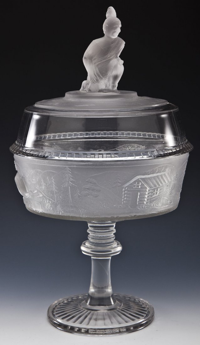 EAPG Westward Ho Compote: DESCRIPTION: EAPG Westward Ho compote. Gillinder & Sons. Colorless and frosted with relief pattern. Clear and frosted lid with Native American finial. MEASUREMENTS: 9" diameter x 15-1/2" high. CONDITI