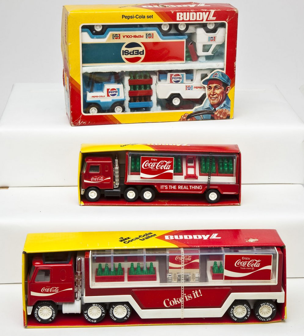 3 Buddy L Cola Trucks: DESCRIPTION: Three Buddy L cola trucks including Pepsi Cola set, Mack Coca Cola trailer, and Coca Cola trailer. MEASUREMENTS: 10-14". CONDITION: All appear unused in original boxes.