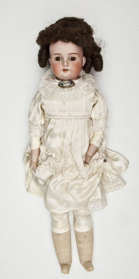 Dressel, Cuno & Otto Bisque Head Doll: DESCRIPTION: Dressel, Cuno & Otto bisque socket head doll with brown glass eyes, open mouth with four teeth, brown replaced wig and kid body with bisque lower arms and fabric lower legs. Back of head 