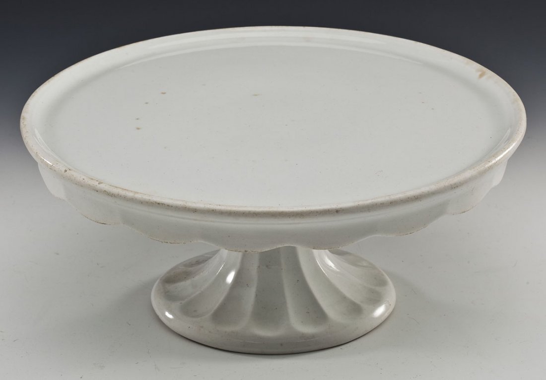 Jacob Furnival & Co. White Ironstone Cake Stand: DESCRIPTION: Jacob Furnival & Co. white ironstone cake stand. Lower scalloped edge. Printed mark underneath for Jacob Furnival & Co. MEASUREMENTS: 11-1/2" diameter x 5" high. CONDITION: Dark spots and