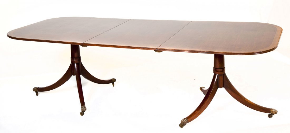 Duncan Phyfe Style Dining Table: DESCRIPTION: Duncan Phyfe style dining table. Two part with tilt sides and center section with clips. Banded mahogany top. Duncan Phyfe style splay legs with brass paws and castors. English, circa 192