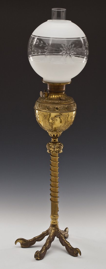 Talon Base Brass Oil Lamp: DESCRIPTION: Talon base brass oil lamp. Scroll motif throughout brass base with corkscrew detail on lower column. Frosted and cut glass shade, floral and leaf motif. Talon or claw foot base. MEASUREME