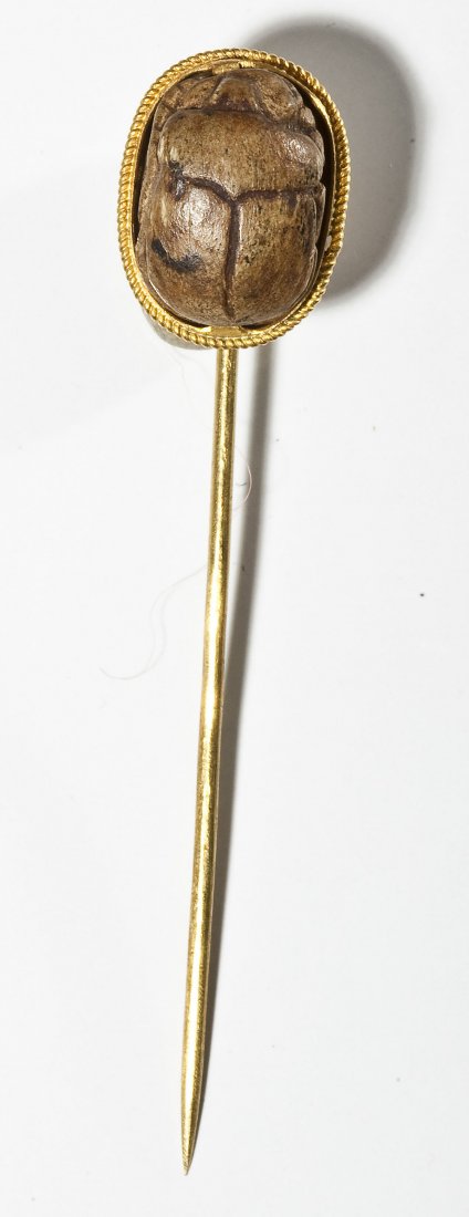 Antique 18K Scarab Pin: DESCRIPTION: Ancient scarab beetle mounted on an 18K yellow gold stickpin. Includes original card from Abd-El-Rahim El Sha'er Antiquities Merchant in Cairo, Egypt. MEASUREMENTS: 2-1/4" long. 2.1 dwt (