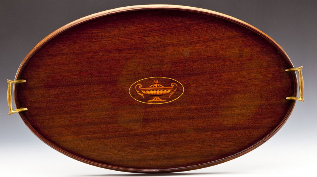 English Mahogany Inlaid Oval Tea Tray: DESCRIPTION: English mahogany inlaid oval tea tray. Center inlaid with image of urn in an oval. Brass handles. Unmarked. MEASUREMENTS: 24-3/4" x 14-3/4". CONDITION: Light surface wear, small area of r