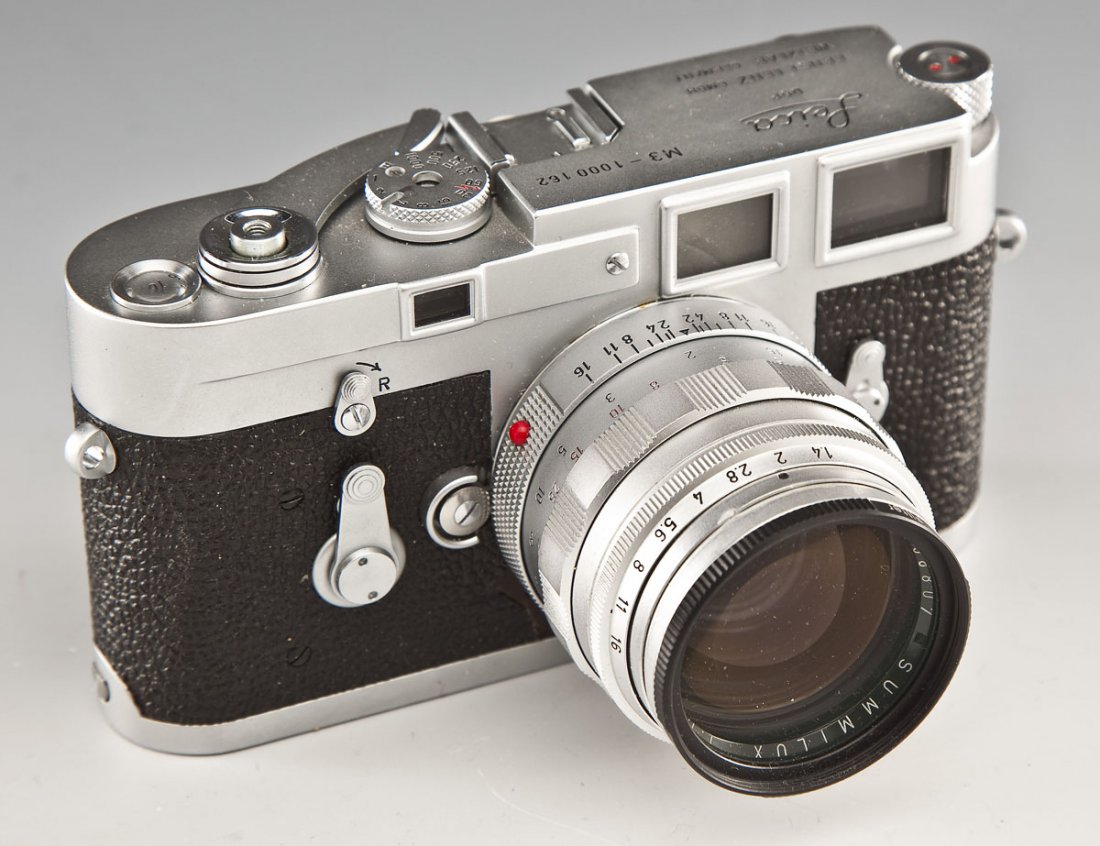 Leica M3 Camera with Summilux Lens: DESCRIPTION: Leica M3 camera serial #1000162, marked Leica DBP Ernst Leitz GMBH Wetzlar Germany. Circa 1960. With Leitz Wetzlar 1758807 Summilux 1:1.4/50 lens. In leather Leica case. MEASUREMENTS: 5-3