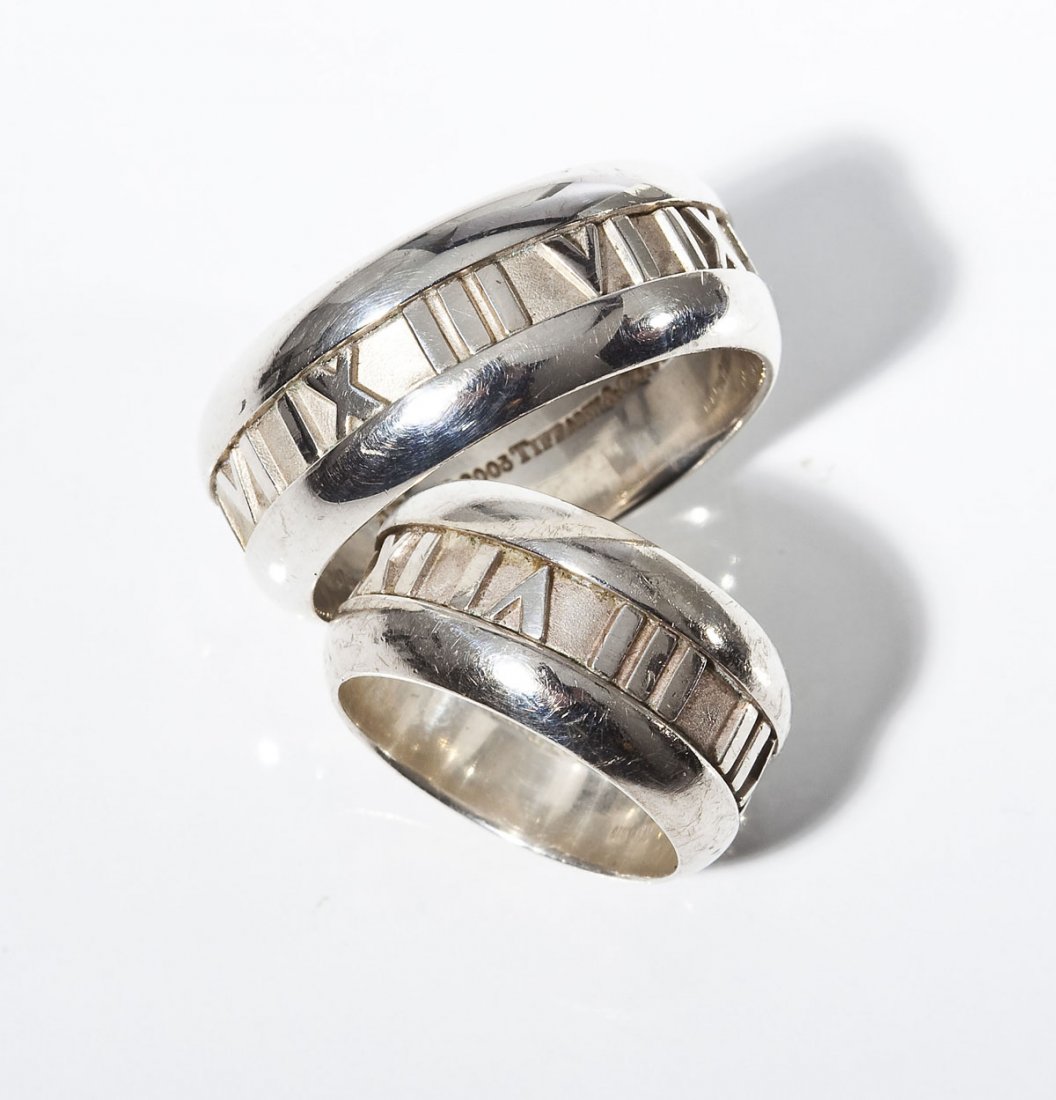 Man's & Lady's Tiffany Atlas Band Rings: DESCRIPTION: Set of man's and lady's Tiffany Atlas band rings. Both marked "Atlas Tiffany & Co 2003 925". Bands with Roman numerals. Includes Tiffany ultrasuede bag. MEASUREMENTS: Lady's size 5. Man's