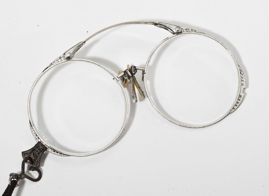 Goldfilled Filigree Lorgnette: DESCRIPTION: White goldfilled folding lorgnette with filigree frame. On black cord and housed in leather case from Euker, Baltimore. MEASUREMENTS: 4" diameter. CONDITION: Minor wear and patina.