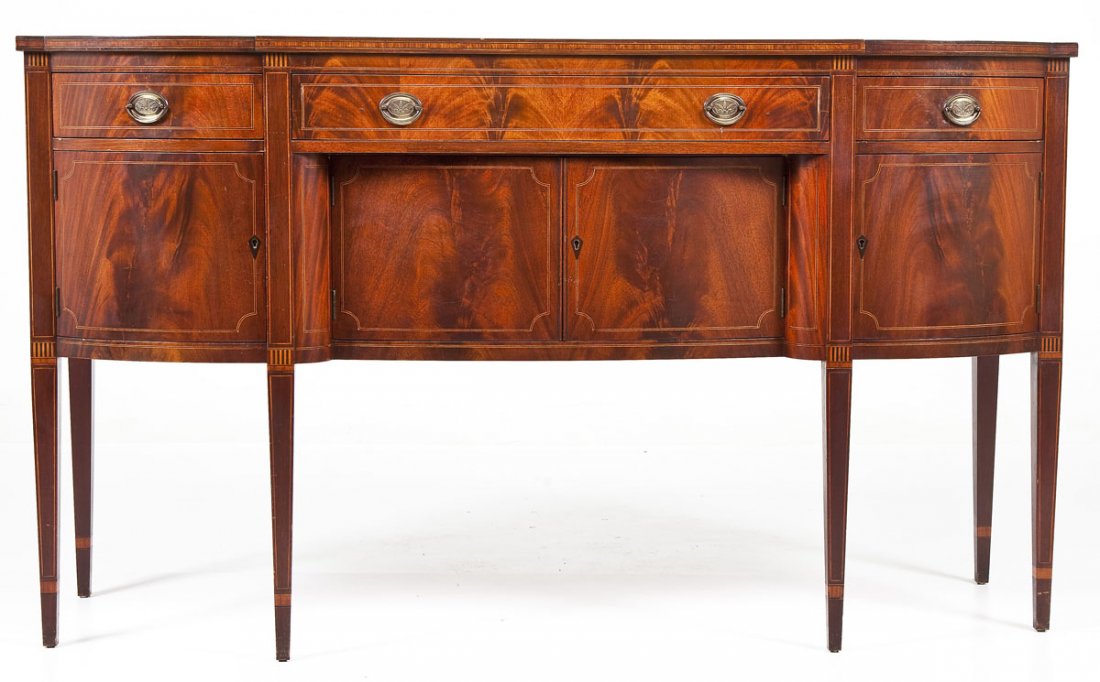 American Federal Revival Hepplewhite Sideboard: DESCRIPTION: An American Federal Revival Hepplewhite sideboard probably Midwestern and early 20th century. The form consisting of a six-leg mahogany veneered curved sideboard with three drawers on top