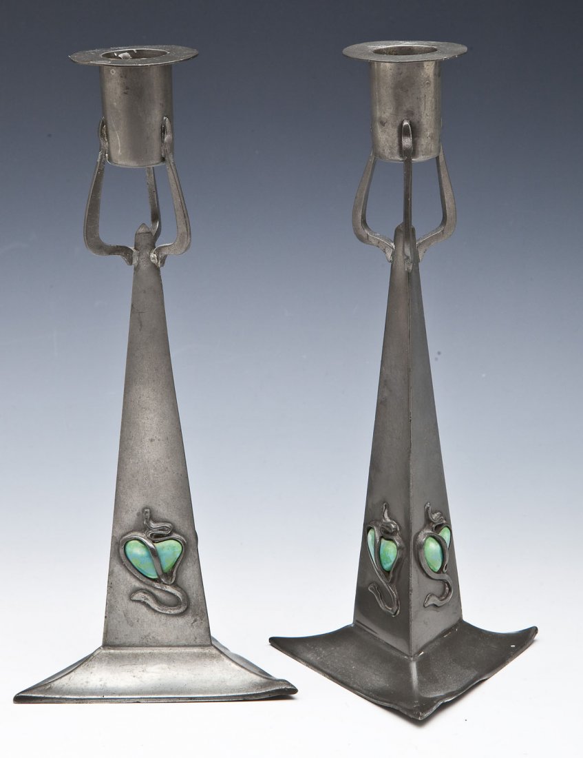 Pair William Hutton & Sons Pewter Candlesticks: DESCRIPTION: Pair of William Hutton & Sons pewter candlesticks. Each with one light, triangle bases and bodies, with snake wrapped enamel hearts on each side. Three arms hold the lights, which have re