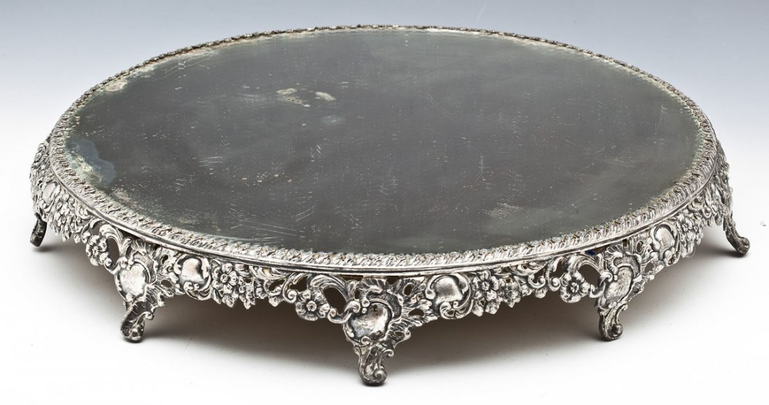 Antique Silverplate Mirrored Plateau: DESCRIPTION: Antique silverplate mirrored plateau with floral and scrolled frame. Unmarked. MEASUREMENTS: 19" diameter x 3" tall. CONDITION: Scratches and wear to silvering of mirror. Minor warping to