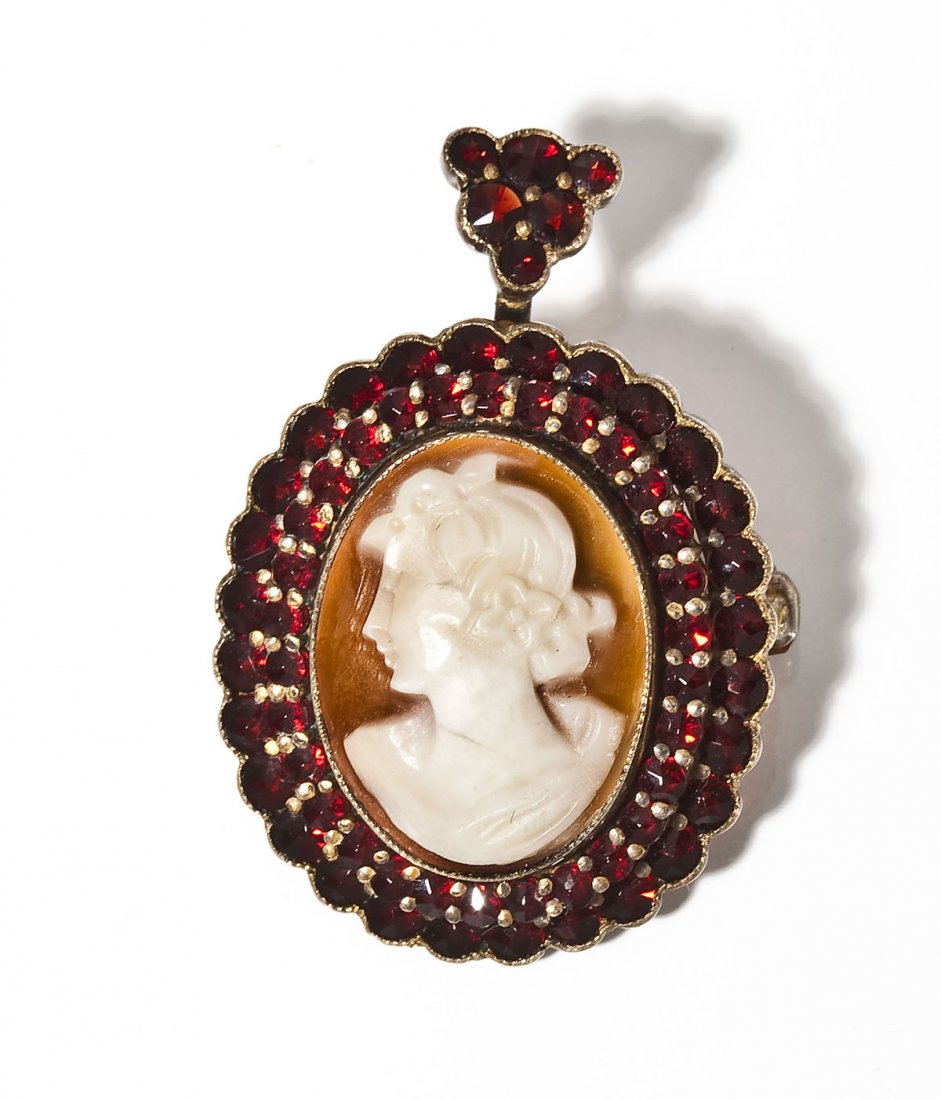 Victorian Cameo & Garnet Pendant/Pin: DESCRIPTION: Victorian pendant/pin with a central shell cameo encircled by a double row of garnets. MEASUREMENTS: 1-1/2" long. CONDITION: No defects noted.