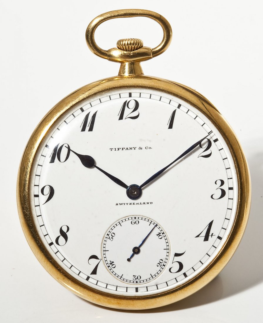 18K Tiffany Pocket Watch by Patek Philippe: DESCRIPTION: Tiffany & Co open face pocket watch. Stem wound, pendant set. White porcelain single sunk dial with subsidiary seconds, Arabic numerals, Poires hands, marked "Tiffany & Co. Switzerland".