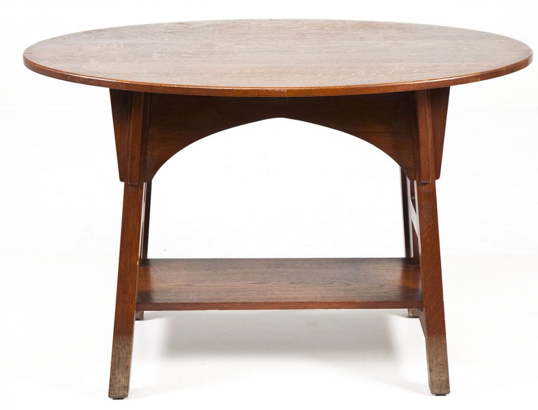 Limbert Oval Library Table: DESCRIPTION: Limbert oval fumed oak library table with trestle base, applied top and typical Arts & Crafts cutouts to sides. Marked under base. MEASUREMENTS: 45" x 30" x 29-1/4" high. CONDITION: Some