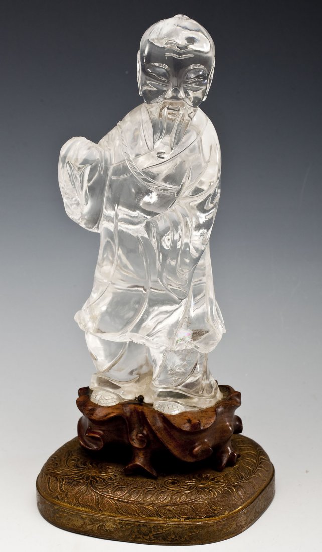 Chinese Rock Crystal Figure: DESCRIPTION: Chinese rock crystal (quartz) figure of a man wearing a bottle around his neck on a wood and brass stand. MEASUREMENTS: 8-1/4" tall x 10-7/8" with stand. CONDITION: Minor chip on right ha