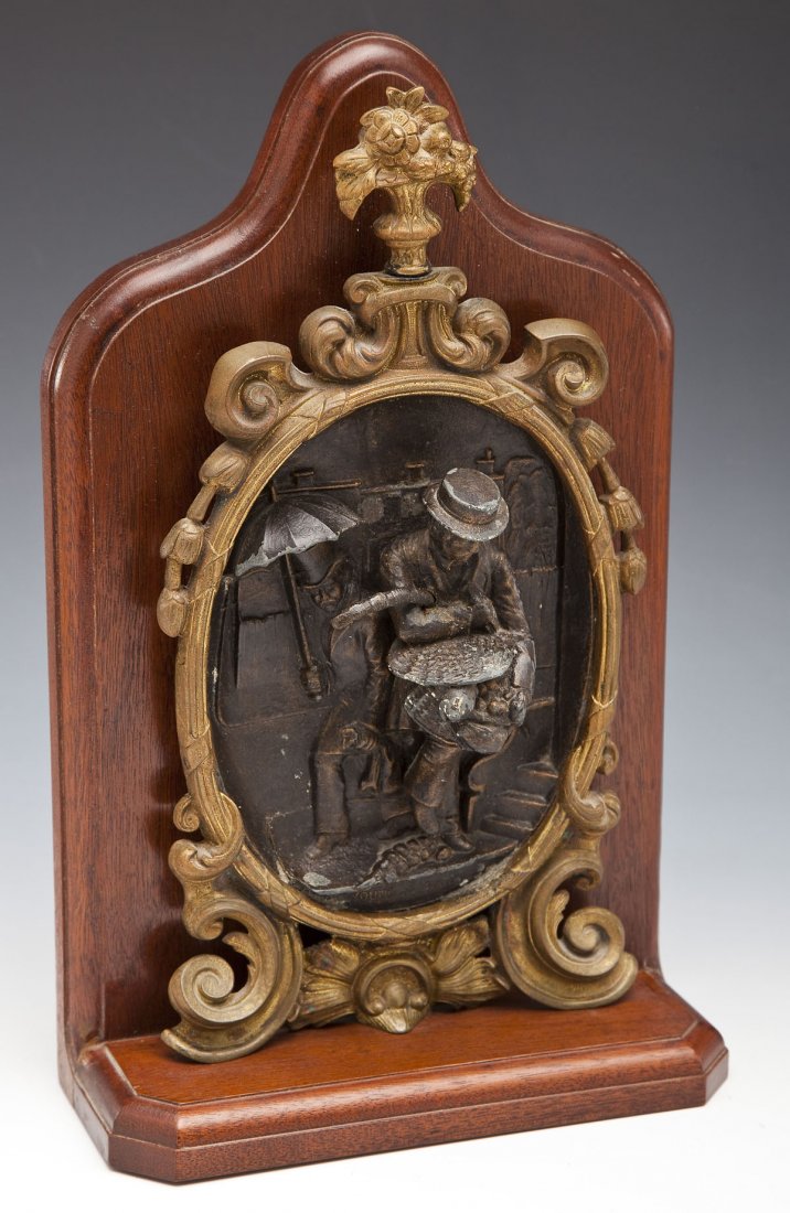 After Lilly Martin Spencer Bronze Wall Plaque: DESCRIPTION: Bronze wall plaque on wood shelf. Based on painting by Lilly Martin Spencer (American, 1822-1902) titled Young Husband: First Marketing, 1854. Bronze in relief depicts husband carrying a