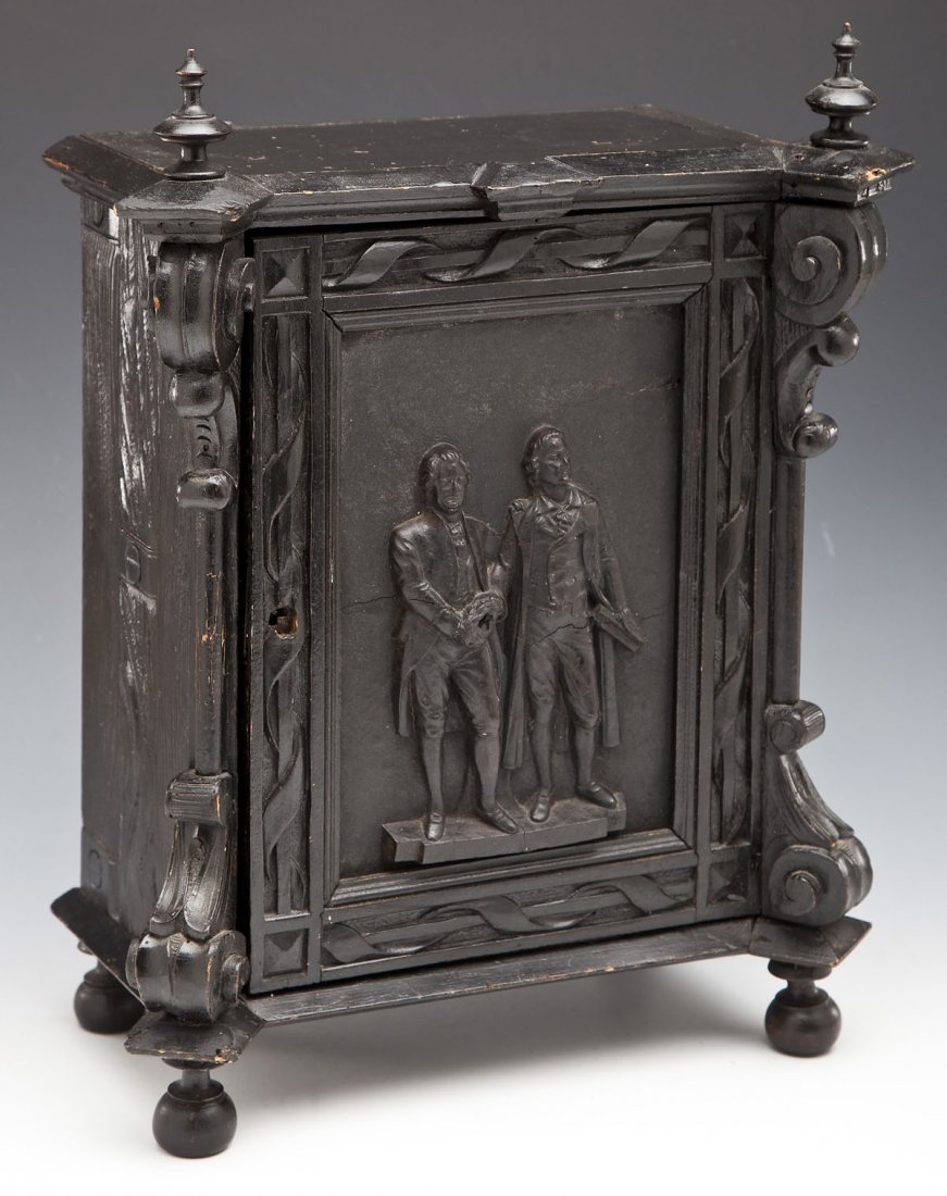 Black Wood Washington & Lafayette Wall Cabinet: DESCRIPTION: Black painted wood carved wall cabinet. Front door with leather covered panel with applied image of Washington holding a laurel wreath and Lafayette holding a document. Inside there are s