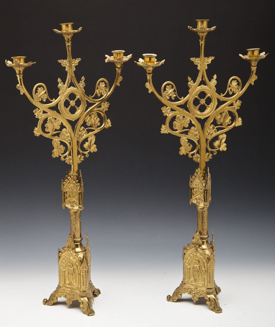Pair of Gothic-Style Candelabras: DESCRIPTION: Pair of ormolu brass Gothic-style candelabras. Tri-footed stand in shape of Gothic church portals. Architectural and floral elements. Each candelabra holds three candles. Third quarter of