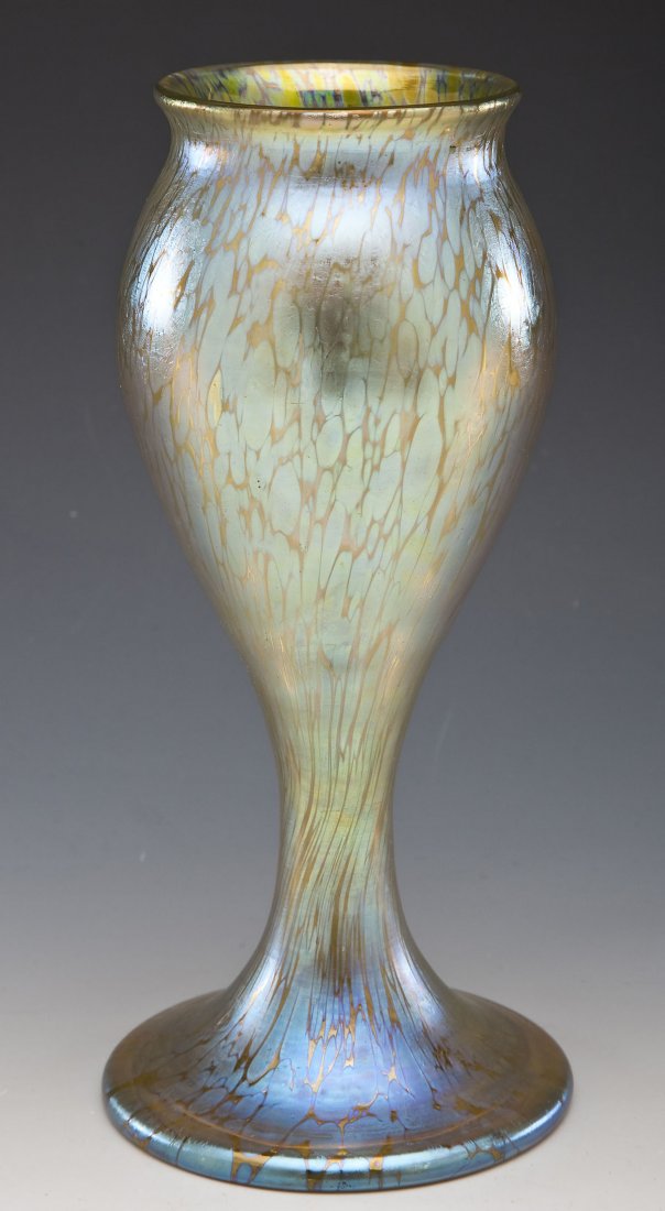 Loetz Type Art Glass Iridescent Vase: DESCRIPTION: Loetz type art glass gold iridescent tall stem vase. MEASUREMENTS: 9-3/4" tall x 3-1/4" diameter x 4-1/2" at widest point. CONDITION: No defects noted.