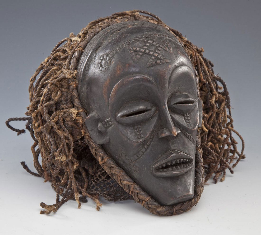 Chokwe Passport Mask: DESCRIPTION: Chokwe mask of diminutive form. Carved chin beneath parted lips and small nose framed by slit eyes and arching brows. An elaborate cap made of braided fibre. The forehead decorated with b