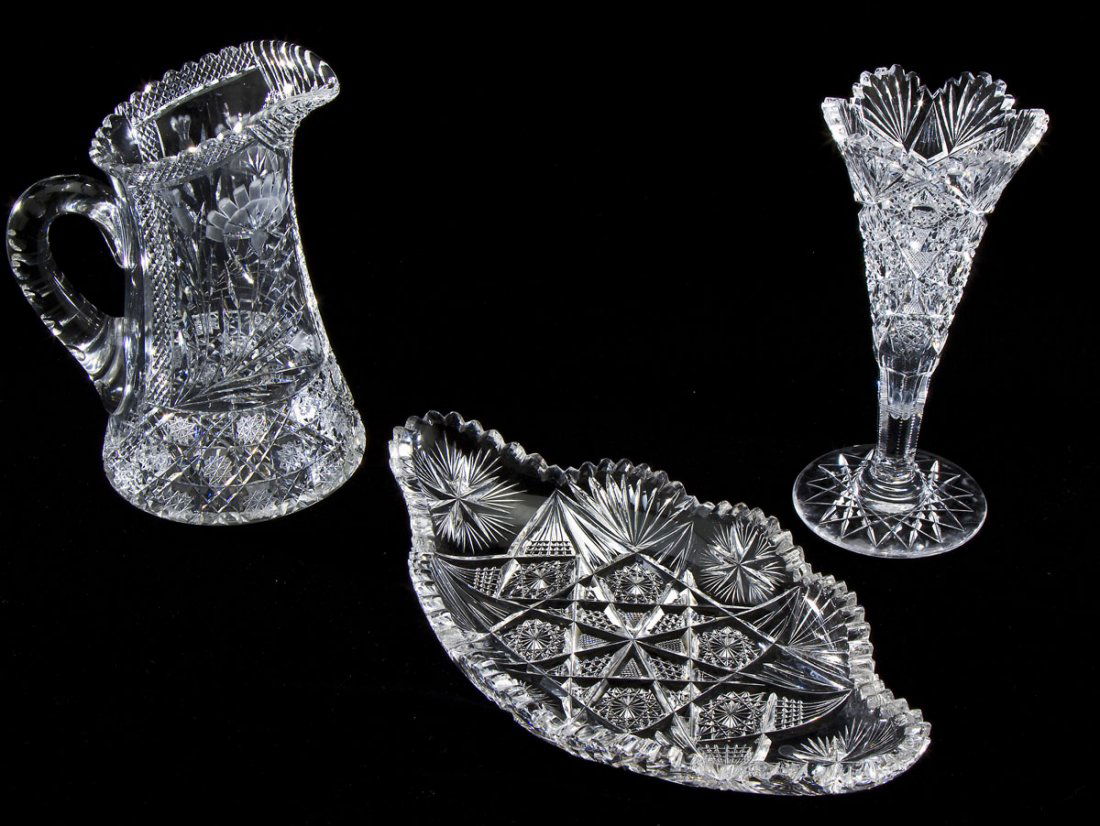 3 Pcs Cut Glass: DESCRIPTION: Three pieces of cut glass. Includes: 1) 9-1/2" trumpet vase. Minor chip to lip. 2) 14-1/4" scalloped serving dish. Minor chips to edges. 3) 9-1/4" tall pitcher. Minor wear throughout. MEA