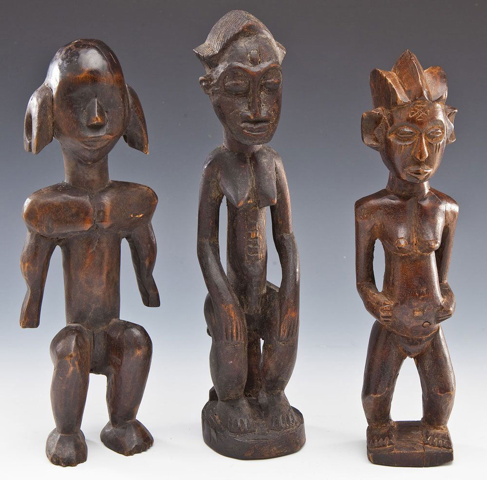 3 Carved African Figures: DESCRIPTION: Three carved African figures. Includes: 1) Male figure with large ears and broad shoulders. Minor cracks to surface. Approximately 12" tall. 2) Female figure with three-lobed coiffure. Mi