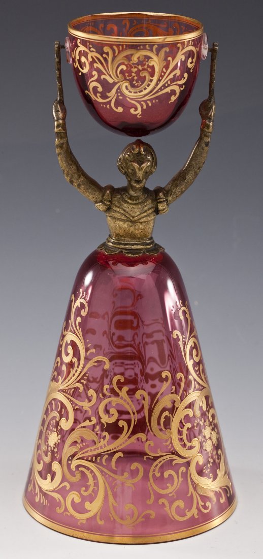Gilt Glass & Bronze Figural Wedding Cup: DESCRIPTION: Gilt glass and bronze figural wedding cup. Pink glass with ornamental scrollwork on both cups. Unmarked. MEASUREMENTS: 8-1/4" tall x 3-3/4" diameter at widest point. CONDITION: No defects