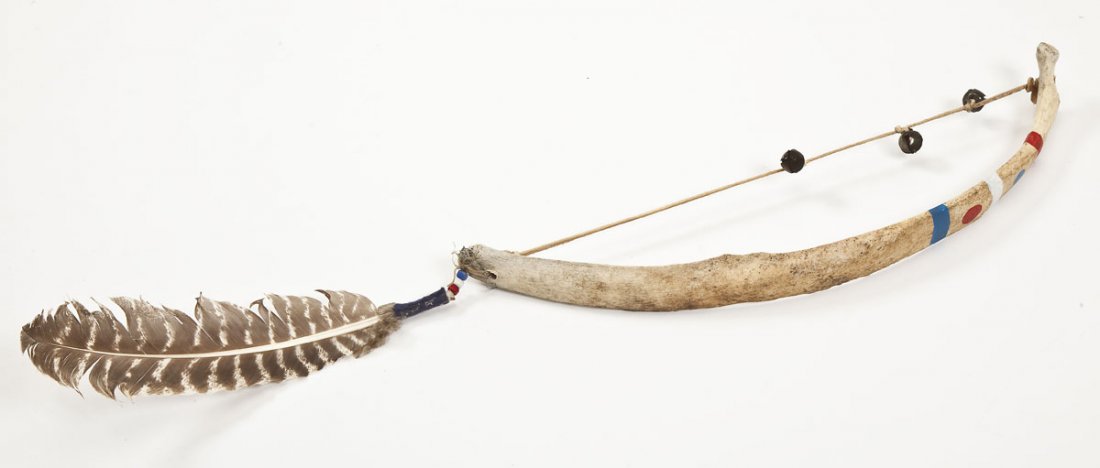 Sioux Buffalo Rib Rattle: DESCRIPTION: Sioux buffalo rib rattle. Painted with red, blue and white stripes and dots. Adorned with a feather, beads, and three bells. MEASUREMENTS: 20-1/2" x 4-3/4". CONDITION: Minor wear to surfa