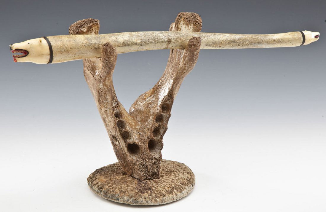 Inuit Decorated Oosik with Walrus Jaw Stand: DESCRIPTION: Inuit decorated oosik with carved ivory polar bear heads. Constructed walrus jaw bone and whale vertebrae stand for oosik. MEASUREMENTS: Oosik: 19-1/2" long. Stand: 10" tall x 8-1/4" at w