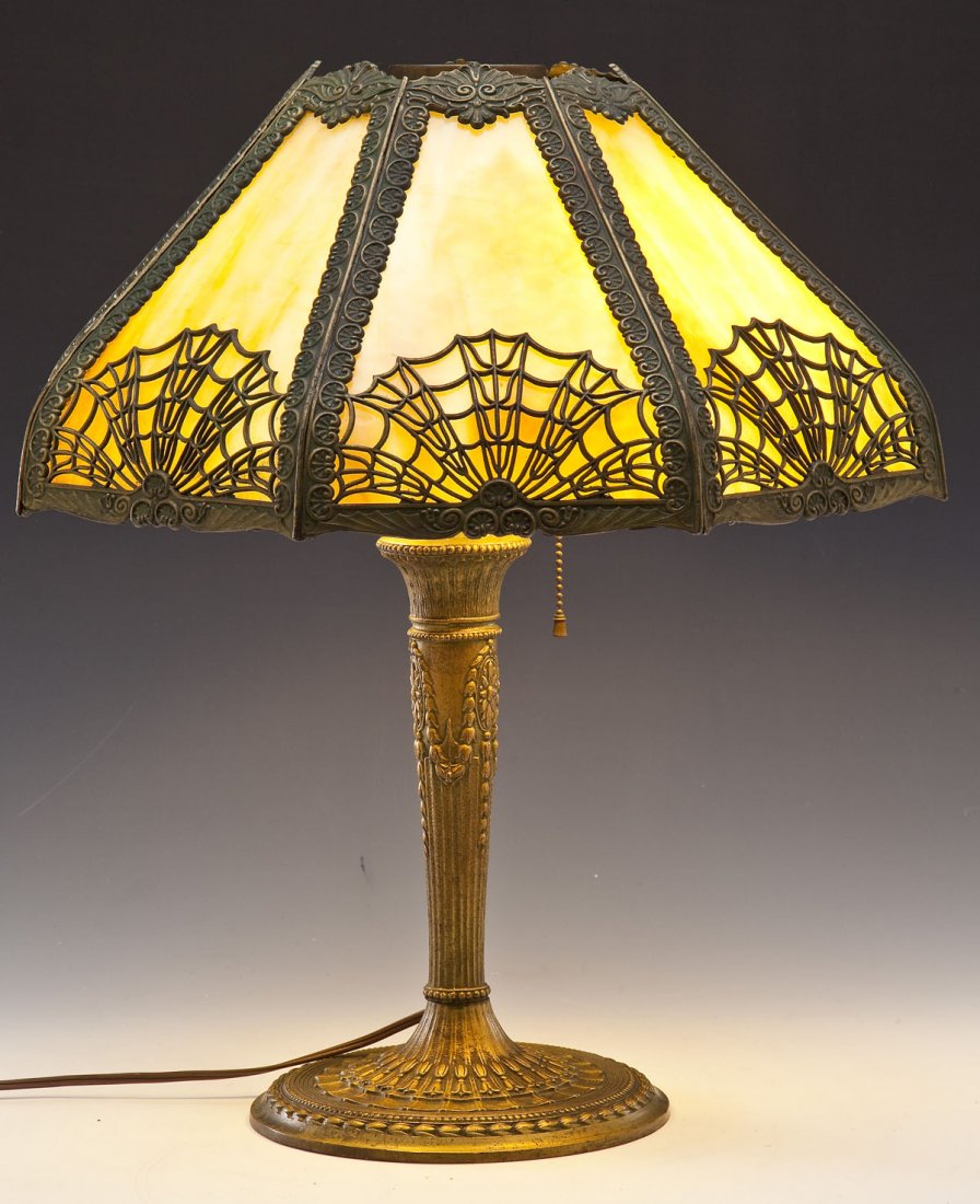 Spider Web Filigree Caramel Slag Glass Lamp: DESCRIPTION: Spider web filigree caramel slag glass lamp. Eight panel shade upon baluster form metal base. Two sockets. Marked "1281" to bottom. MEASUREMENTS: 20-1/2" tall, shade 18-3/4" diameter. Mis